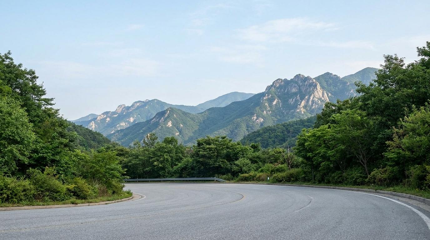 숲으로 둘러싸인 산길과 설악산 일대 능선을 표현한 드라이브 이미지