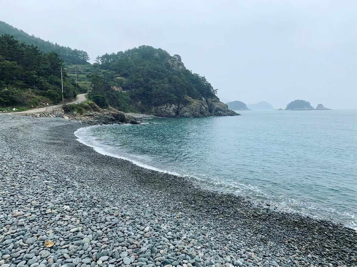 둥근 몽돌과 잔잔한 물결이 이어지는 남해 해변의 분위기를 표현한 이미지